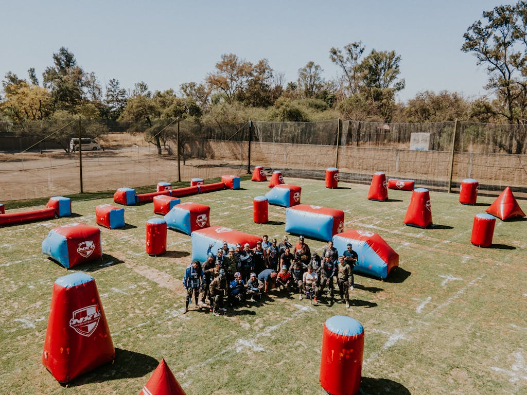 An aerial view of a group of people playing paintball on a marked field outdoors.