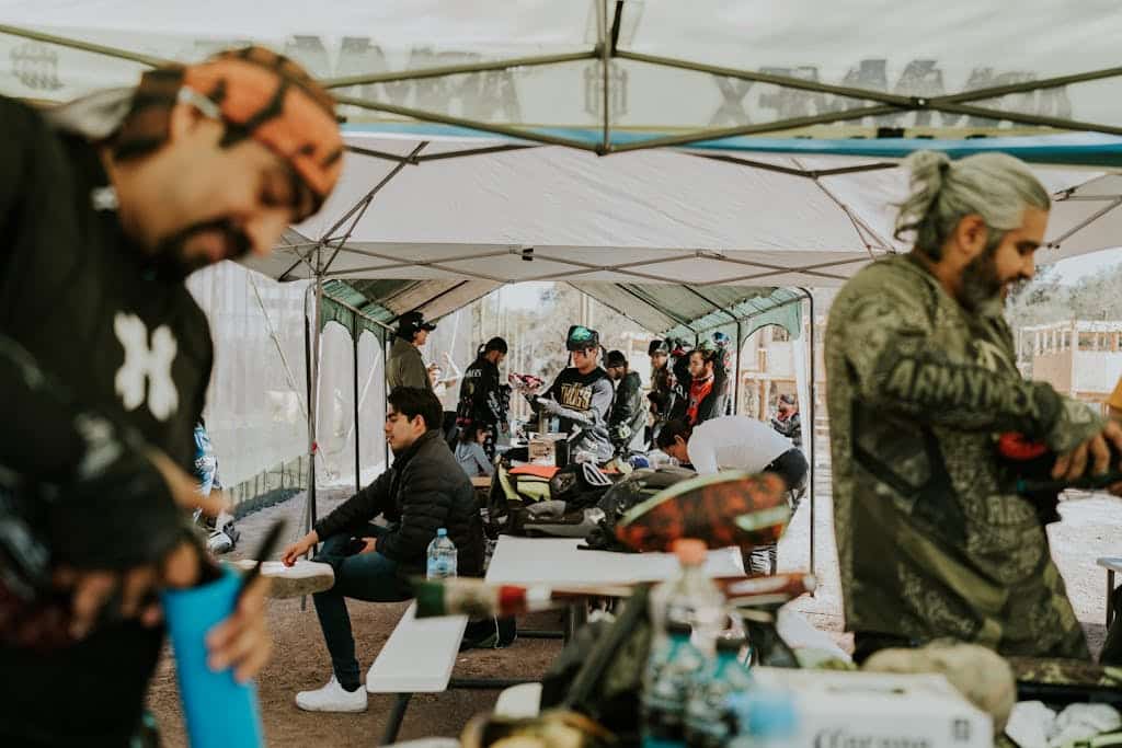 Paintball enthusiasts in protective gear preparing for an exciting match under a large canopy.
