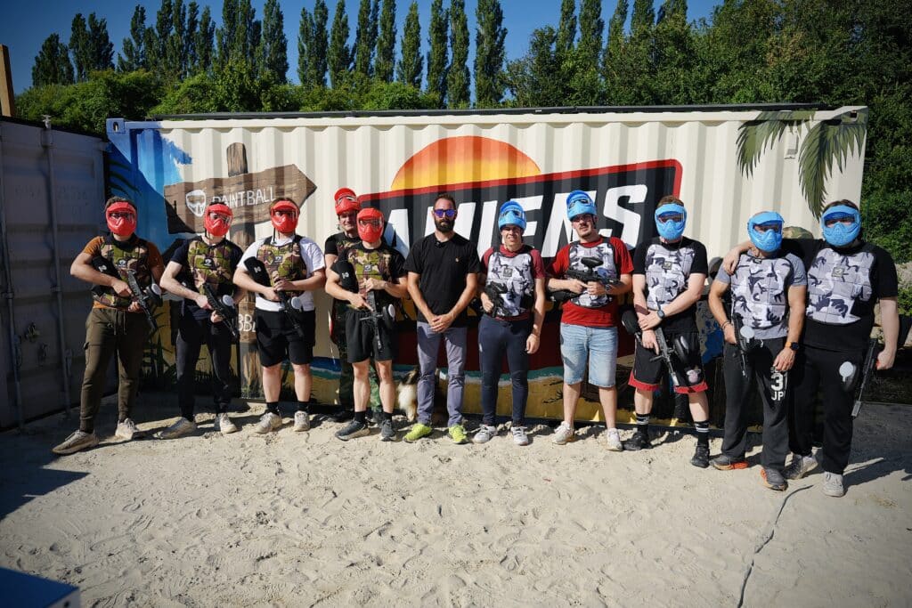 Un groupe de personnes posant devant le logo de Amiens Paintball