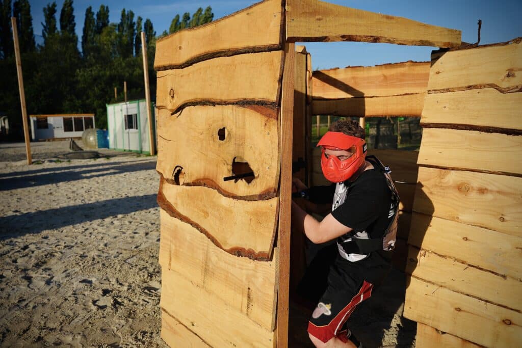 Joueur de gellyball à Amiens à couvert derrière une structure en bois sur le terrain d'Amiens Paintball